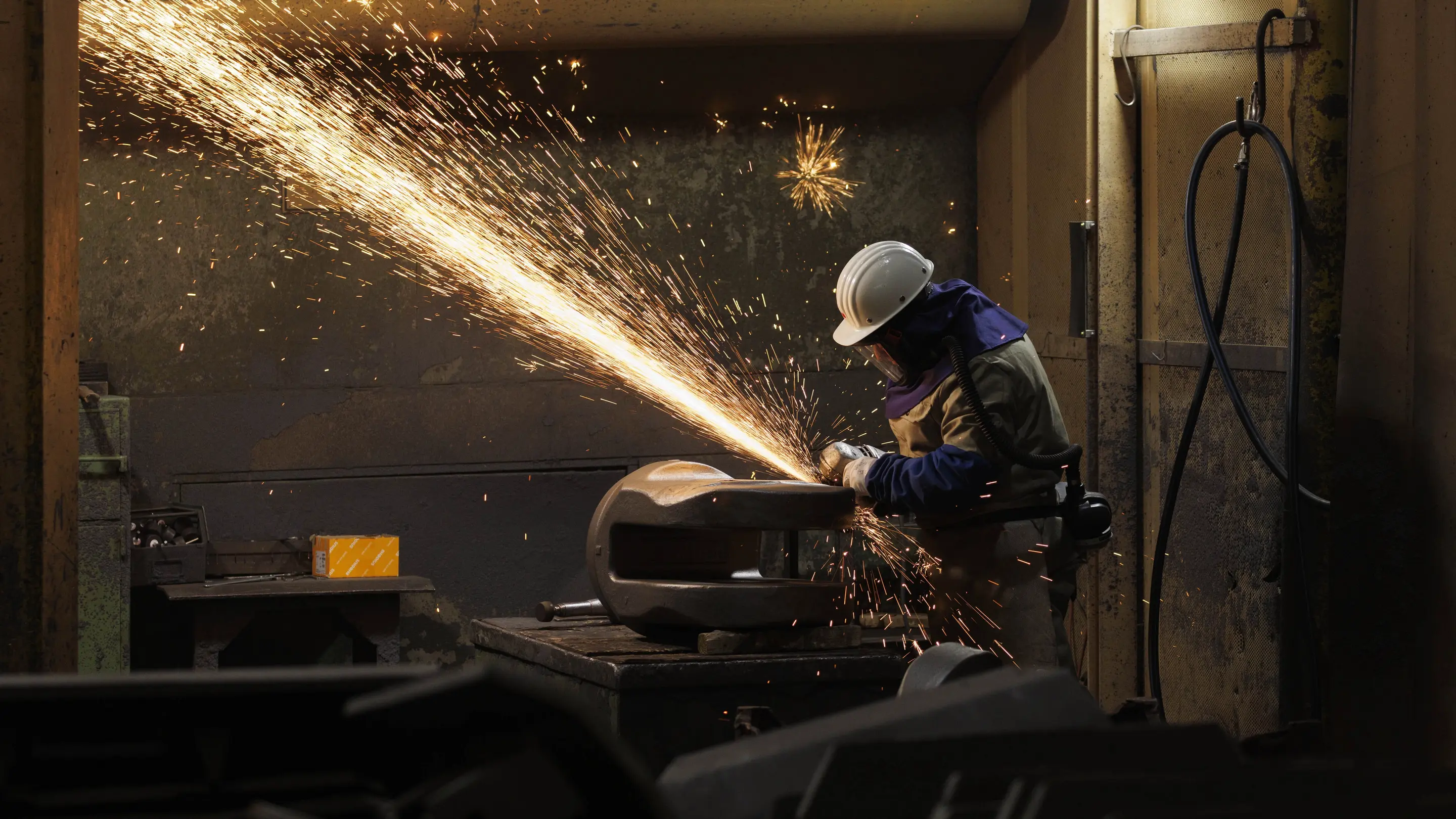 Ein Arbeiter flext ein fertiges Stahlbauteil 