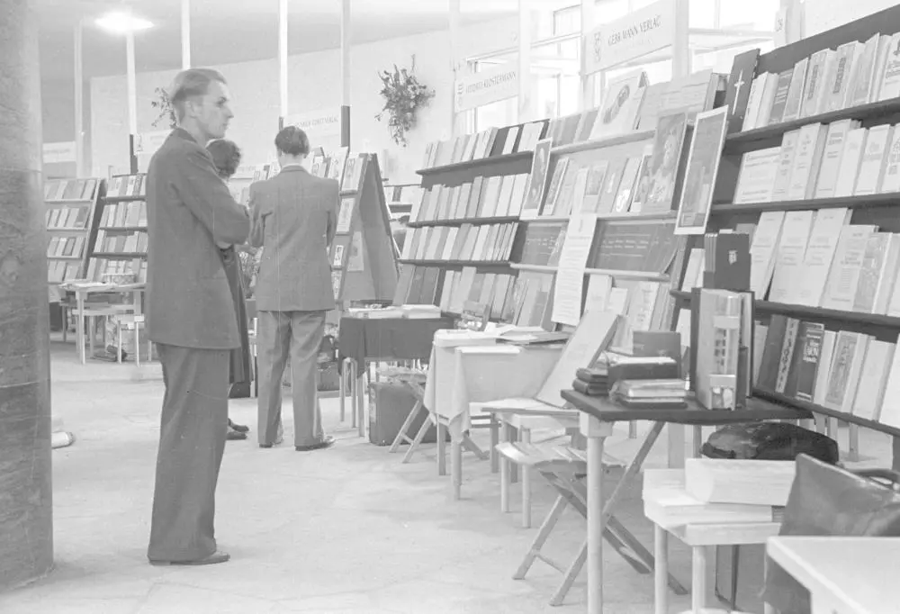 Das Bild zeigt einen Besucher bei der Buchmesse 1949. Der Besucher betrachtet einen Messestand mit Büchern.