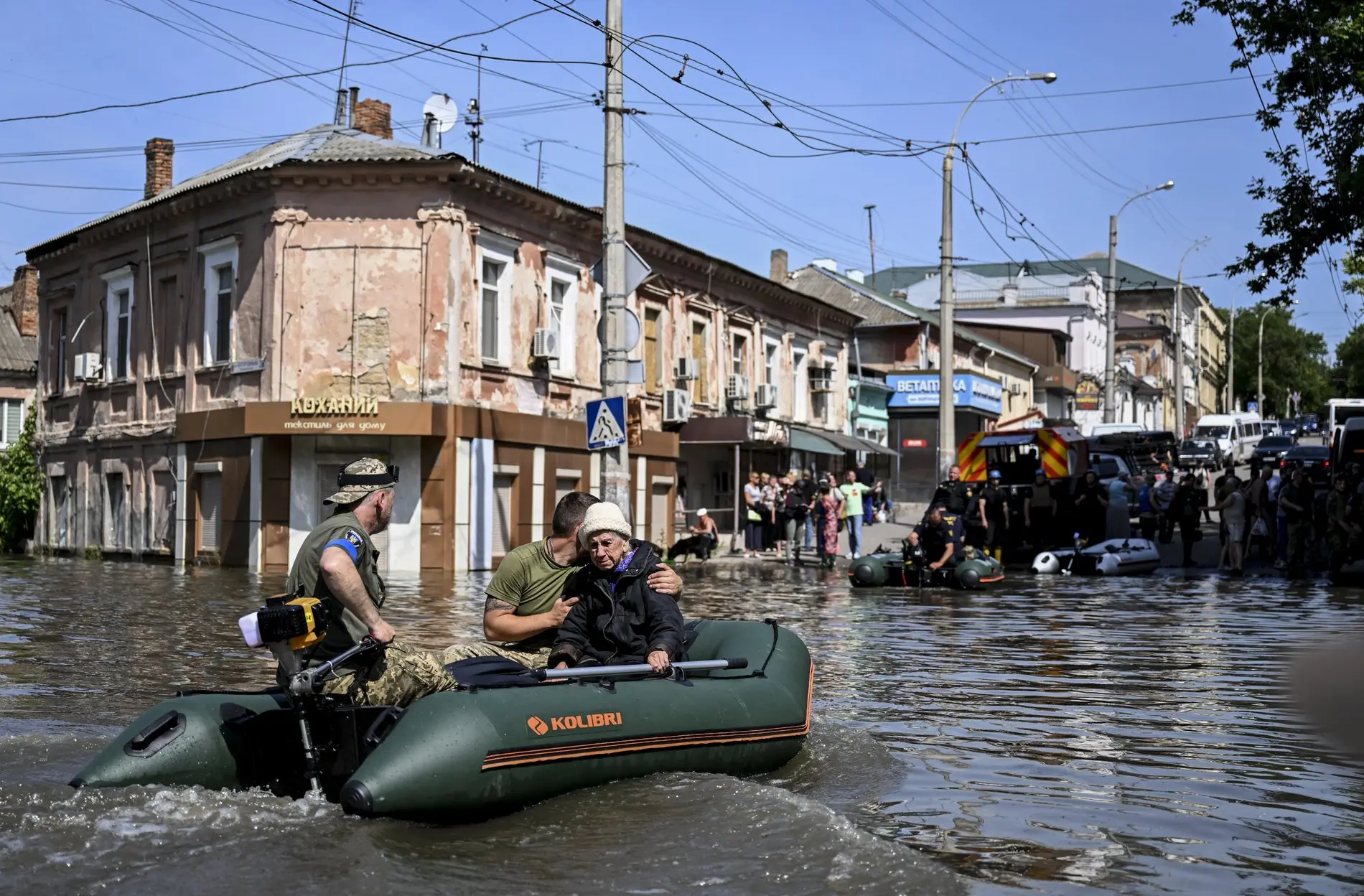 Helfer mit einer älteren Dame in einem Schlauchboot auf überschwemmten Straßen