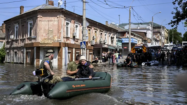 Helfer mit einer älteren Dame in einem Schlauchboot auf überschwemmten Straßen