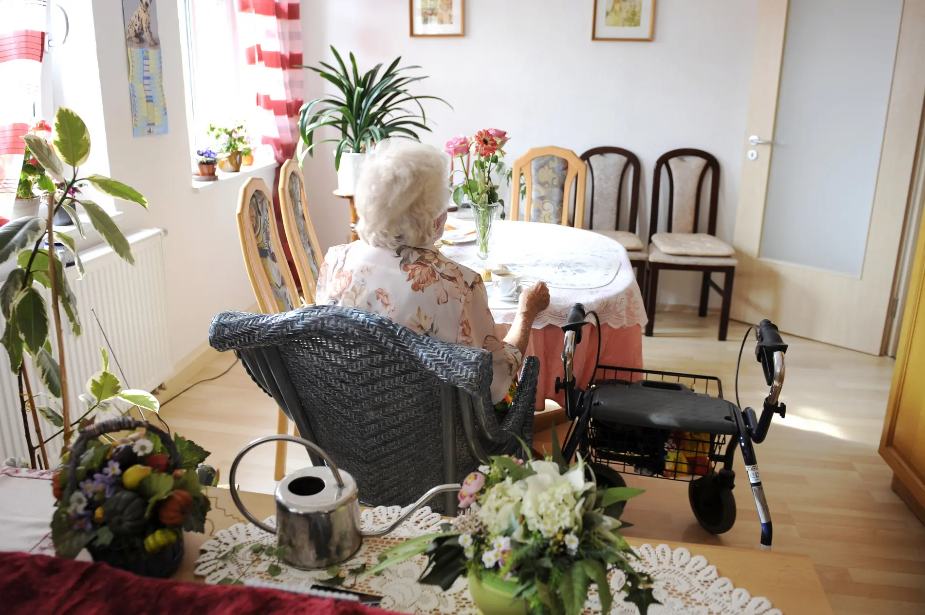 Eine ältere Frau sitzt alleine an einem Tisch