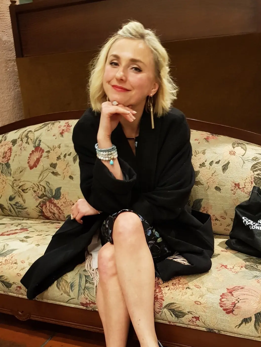 Ina Lechmann in einem schwarzen Mantel sitzend auf einem Sofa