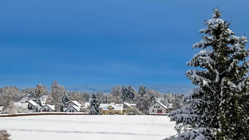 Das Bild zeigt eine Winterlandschaft mit verschneiten Dächern.