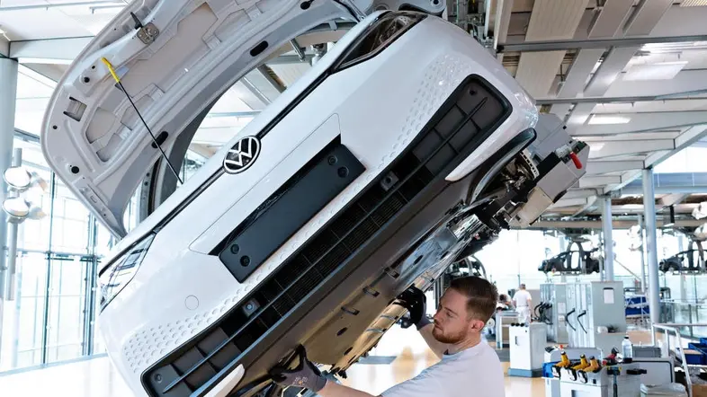 Das Bild zeigt einen Mann bei der Montage eines Autos in einer Fabrik von Volkswagen.
