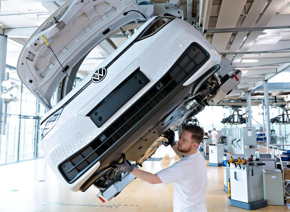 Das Bild zeigt einen Mann bei der Montage eines Autos in einer Fabrik von Volkswagen.