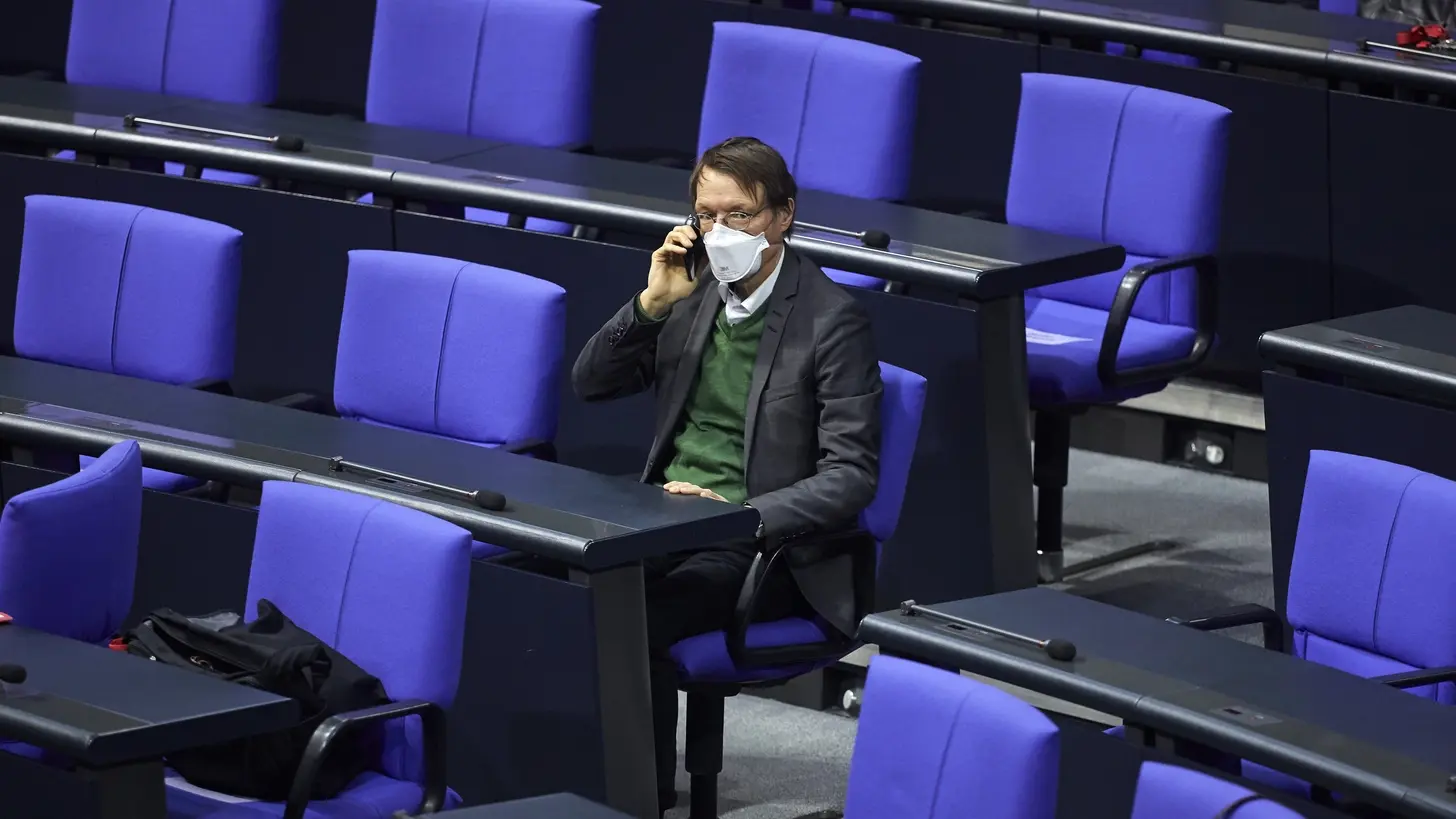 Gesundheitsminister Karl Lauterbach (SPD) Karl Lauterbach sitzt allein mit Maske im Plenum des Deutschen Bundestages.