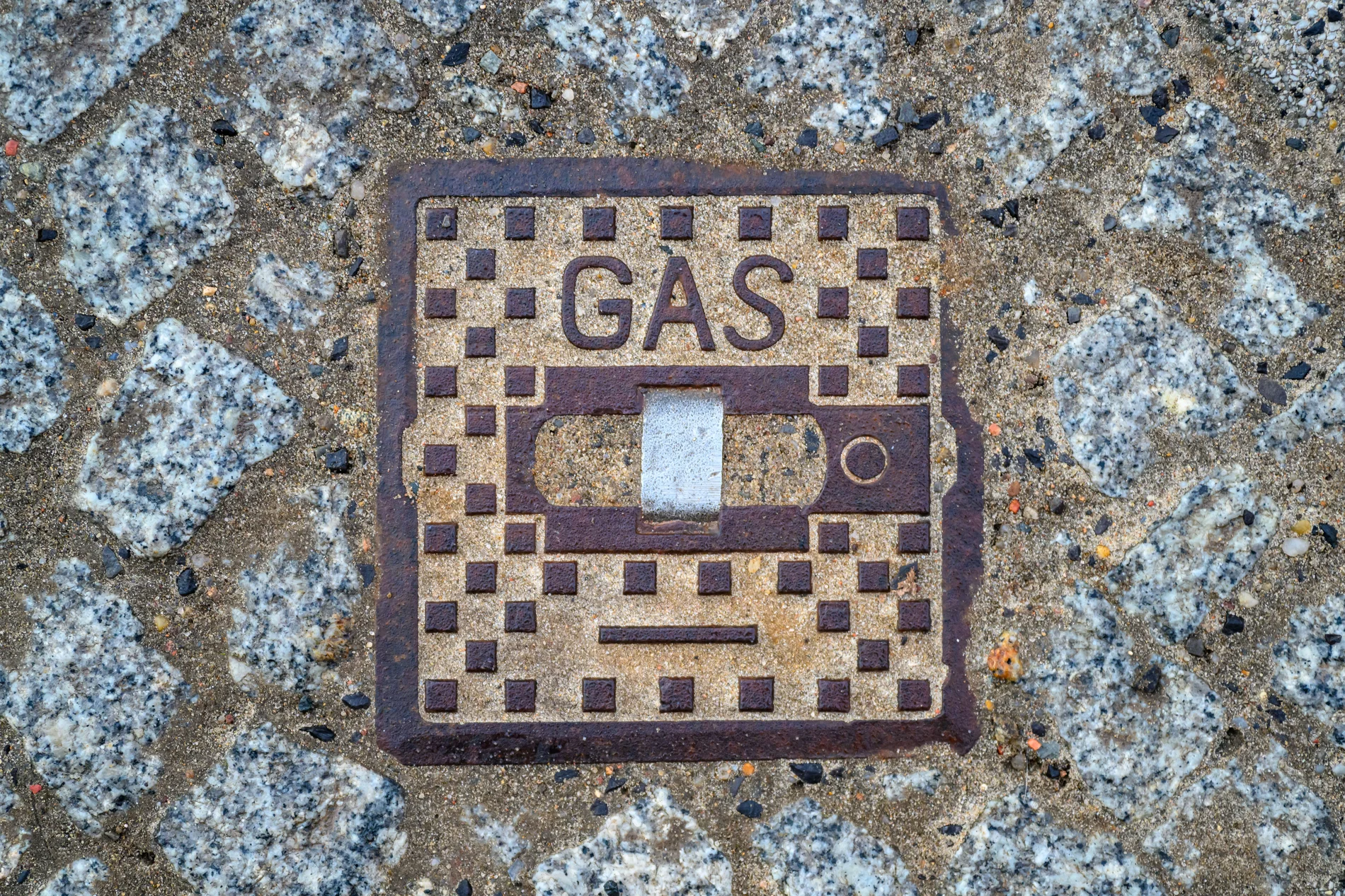 Auf einer Metallplatte im Fußweg steht das Wort "Gas"