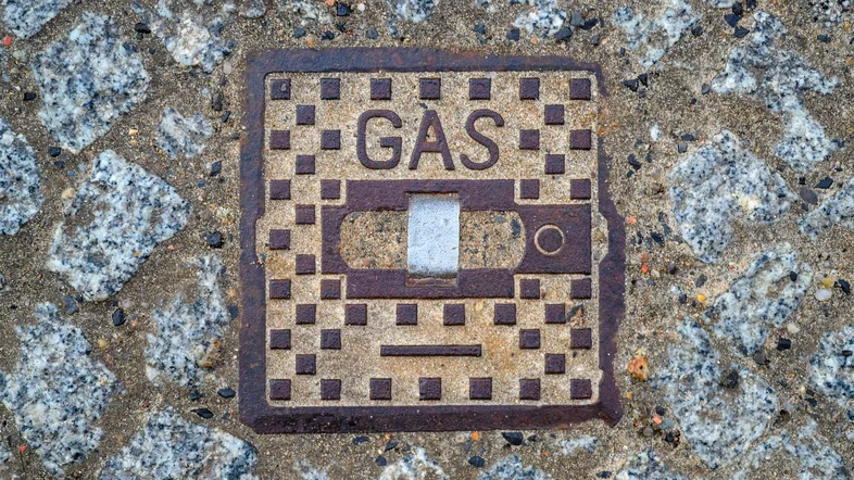 Auf einer Metallplatte im Fußweg steht das Wort "Gas"