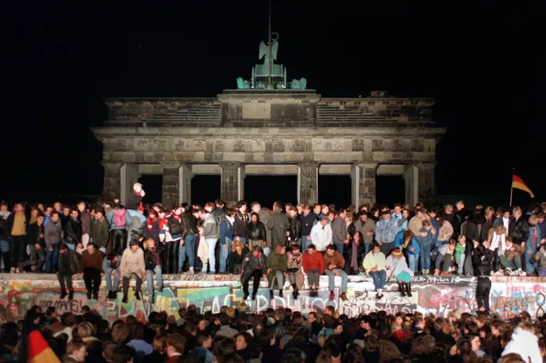 Jubelnde Menschen auf der Berliner Mauer am Brandenburger Tor am 10.11.1989.