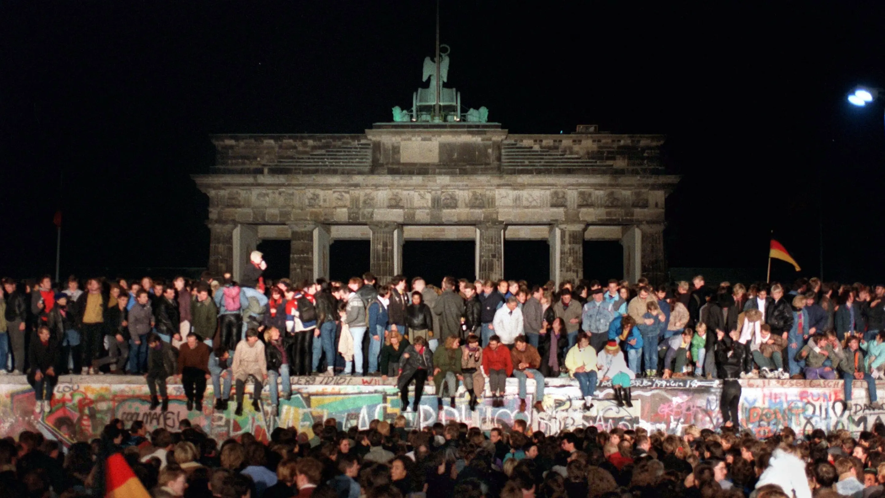 Jubelnde Menschen auf der Berliner Mauer am Brandenburger Tor am 10.11.1989.