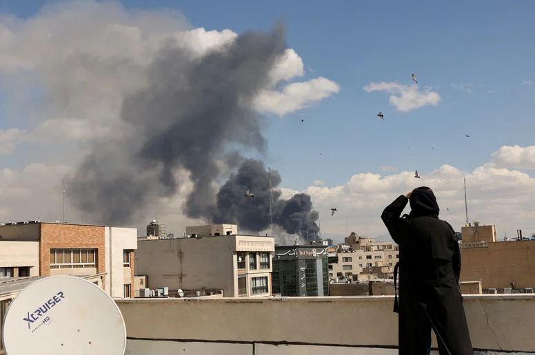 Eine Person blickt vom Dach eines Hauses auf eine Explosion in Teheran