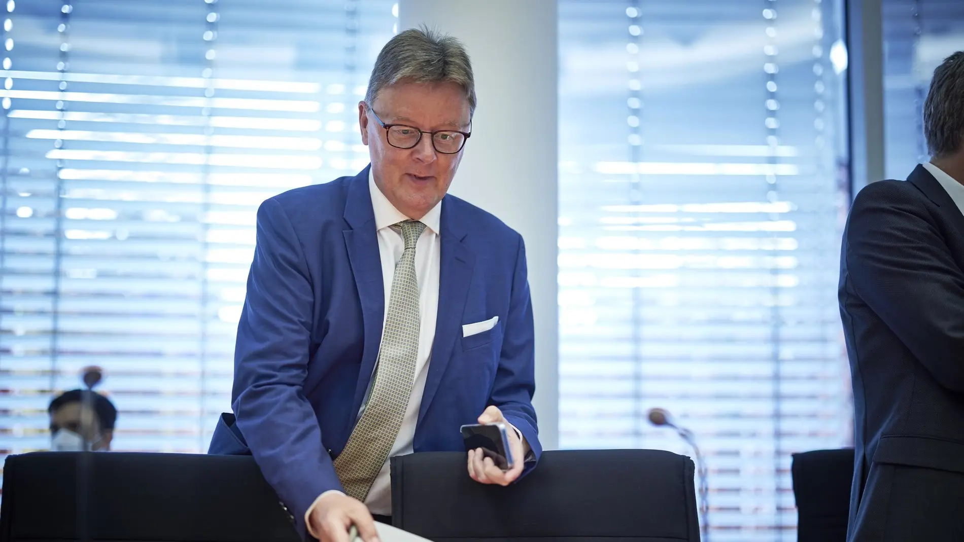 Michael Grosse-Brömer im Anzug mit Krawatte und Brille legt Unterlagen ab.