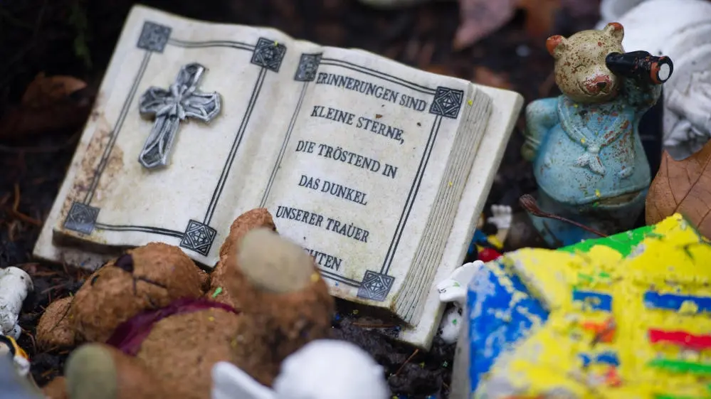 Ein Gebetbuch aus Stein und Spielzeugfiguren auf dem Friedhof