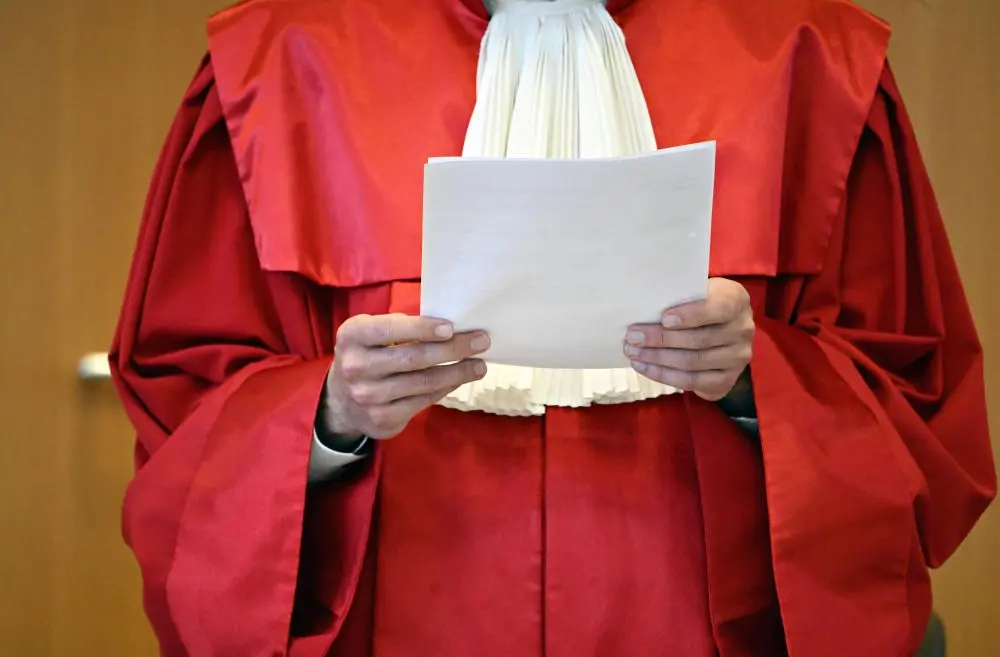 Mann in roter Robe hält einen Stapel Papier