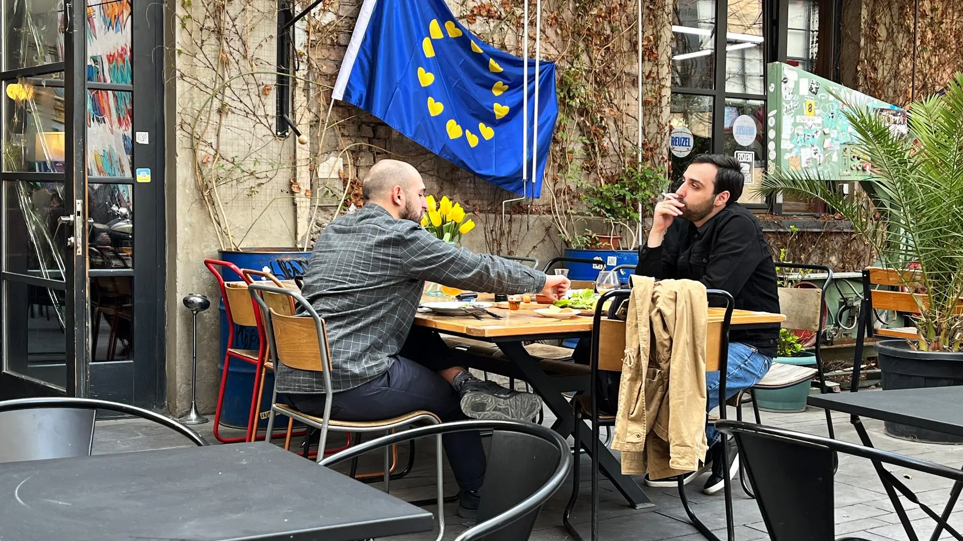 Zwei Männer spielen Schach in einem Café in Tiflis vor einer EU-Fahne.