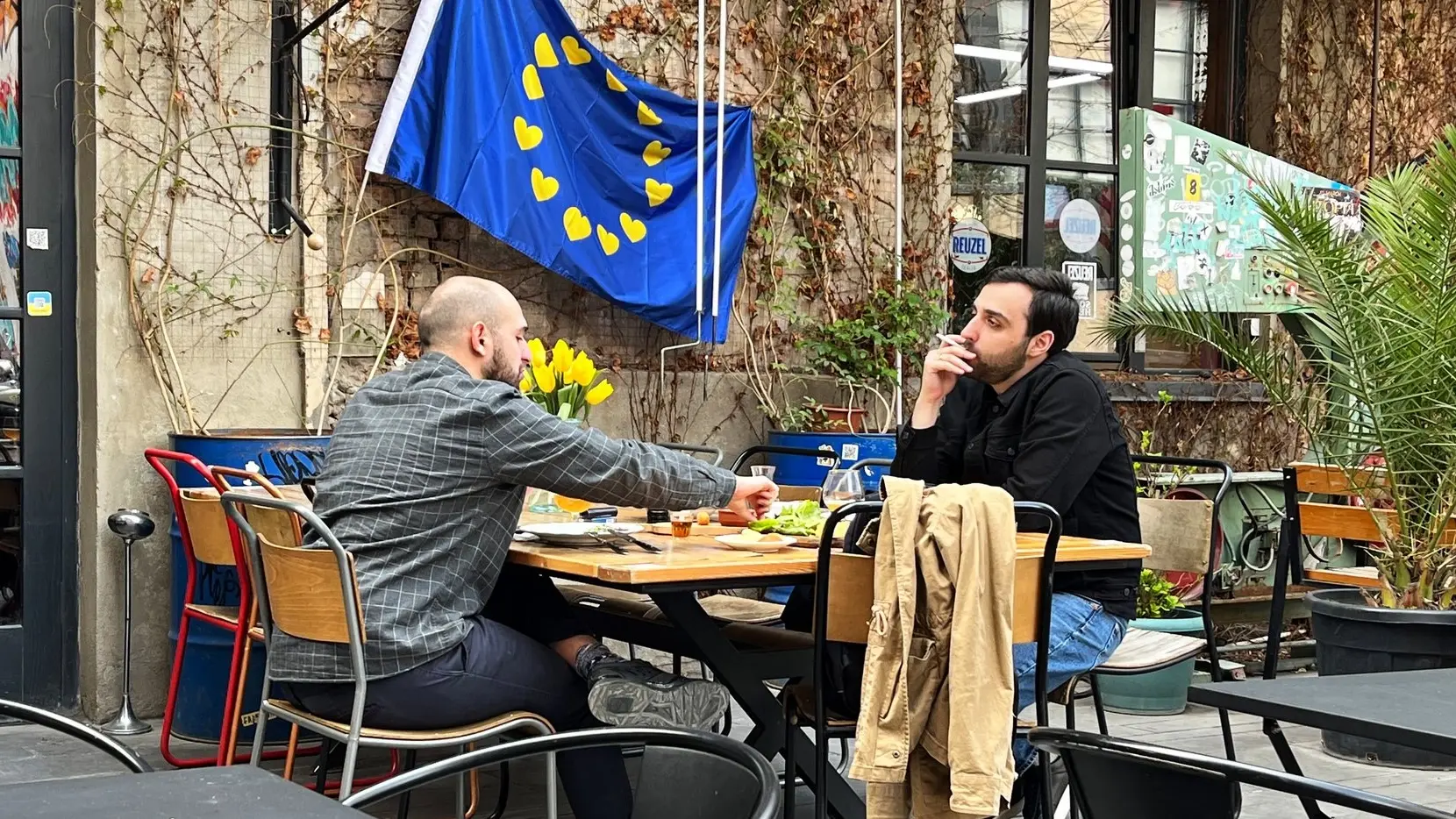 In Georgien will die Bevölkerung mehrheitlich den EU-Beitritt. Zwei Männer spielen Schach in einem Café in Tiflis vor einer EU-Fahne.