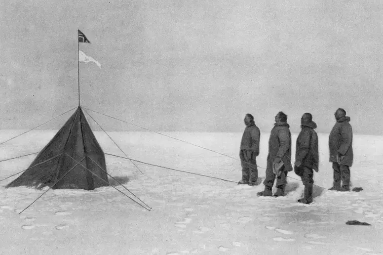 Roald Amundsen und seine Mannschaft blicken am Südpol auf die norwegische Flagge