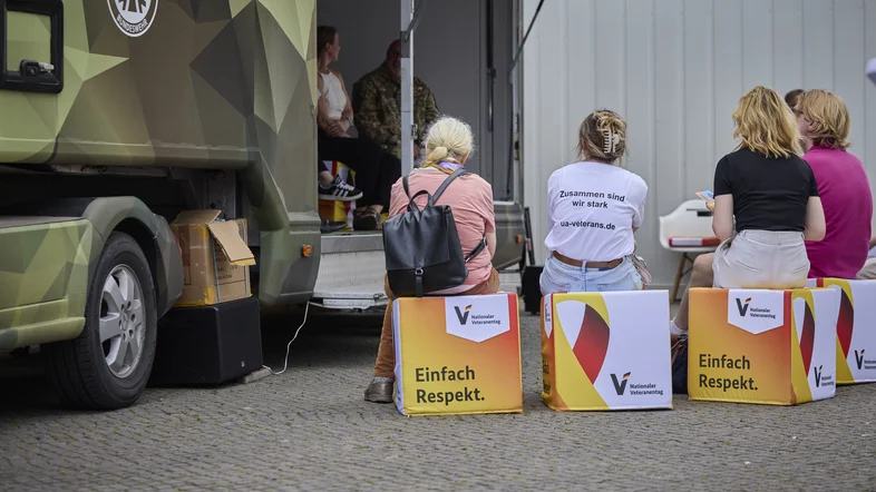 Besucherinnen auf Hockern vom Veteranentag mit der Aufschrift "Einfach Respekt"