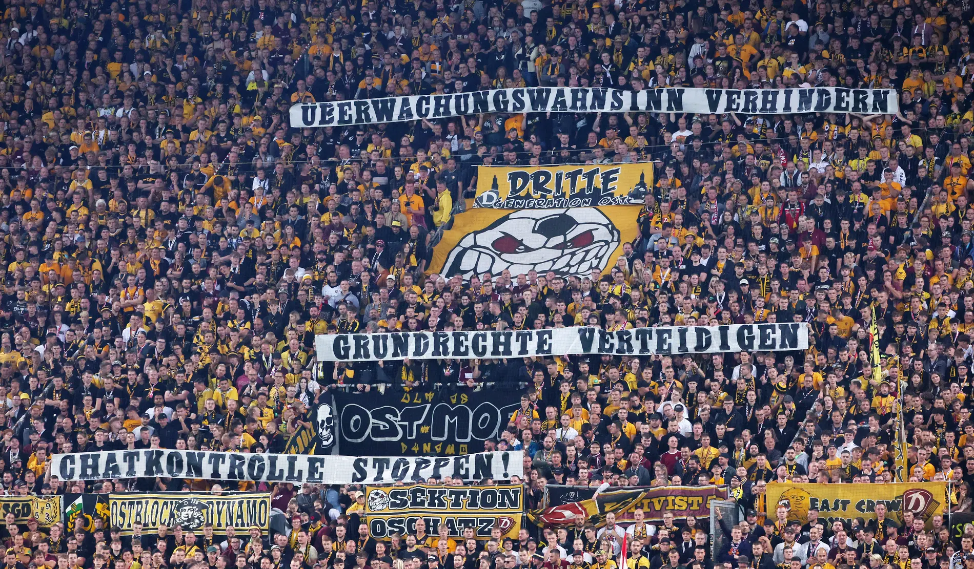 Fans von Dynamo Dresden zeigen ein Plakat. Überwachungswahn verhindern, Grundrechte verteidigen, Chatkontrolle stoppen.