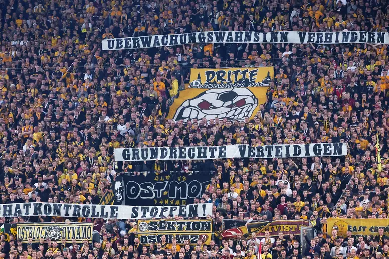 Fans von Dynamo Dresden zeigen ein Plakat. Überwachungswahn verhindern, Grundrechte verteidigen, Chatkontrolle stoppen.