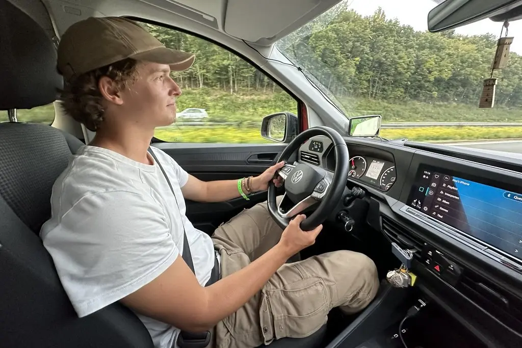 Ein junger Mann am Steuerrad eines Autos.