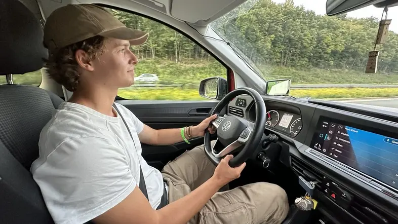 Ein junger Mann am Steuerrad eines Autos.