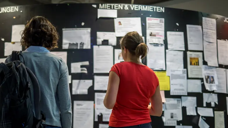 Studentinnen betrachten Wohnungsanzeigen in der Mensa der Universität München