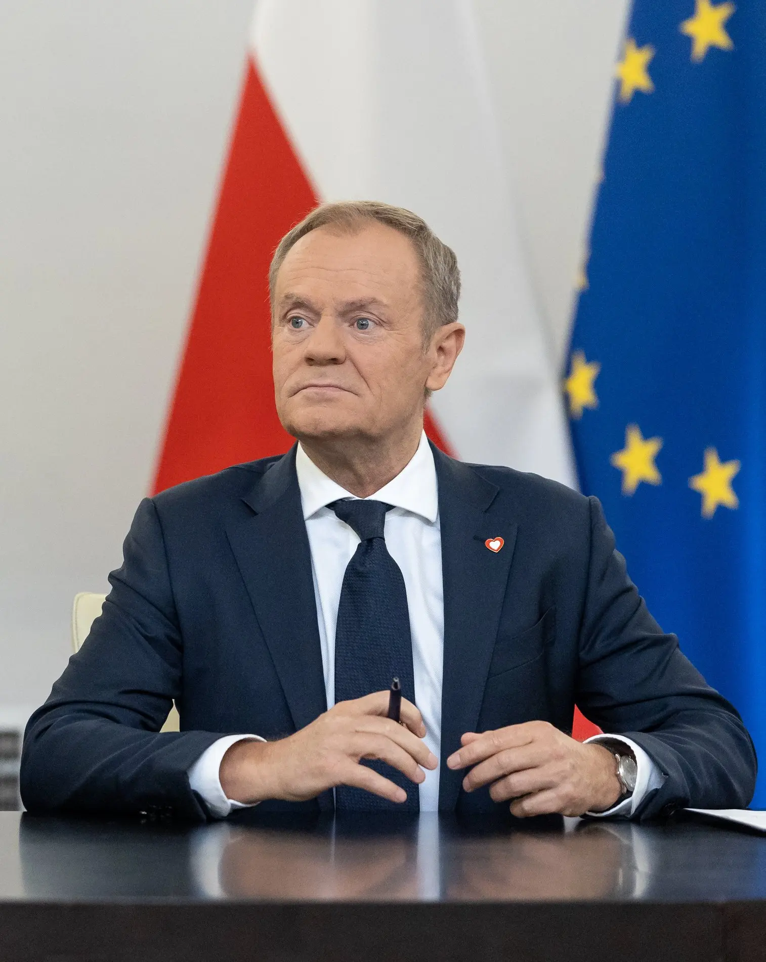 Dolald Tusk sitzt vor europäischer und polnischer Fahne