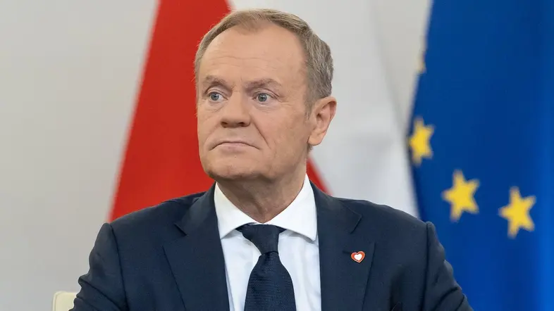 Dolald Tusk sitzt vor europäischer und polnischer Fahne