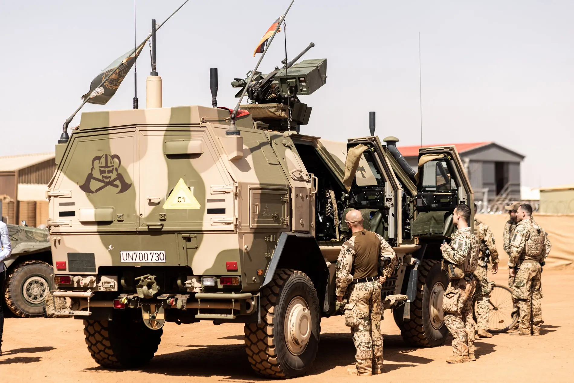 Deutsche Soldaten stehen in in der Wüste vor einem Fahrzeug der Bundeswehr.