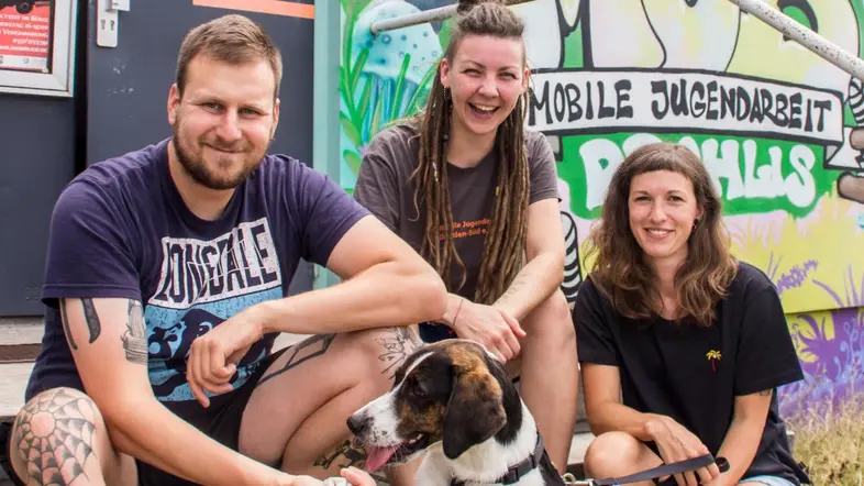 Das Team von Prohlis lächelt mit einem Hund