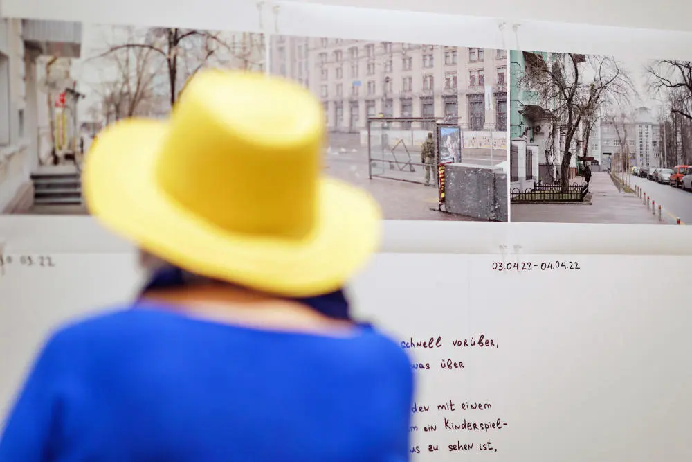 Installation "Nebenan - Das Kiewer Kriegstagebuch" im Reichstagsgebäude Person mit gelbem Hut und blauem Oberteil von hinten fotografiert