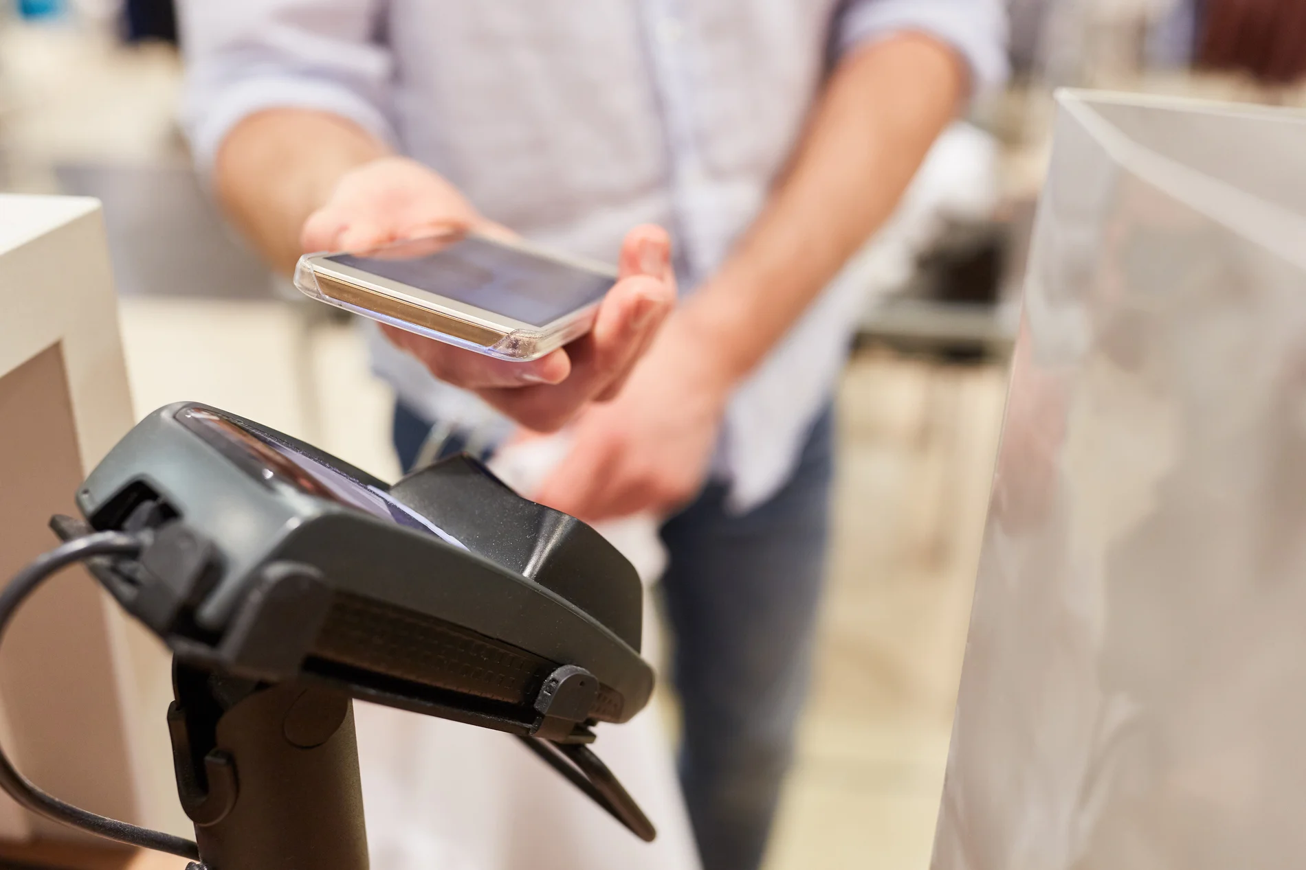 Kunde bezahlt mit NFC Smartphone am Kartenterminal Kasse im Shoppingcenter