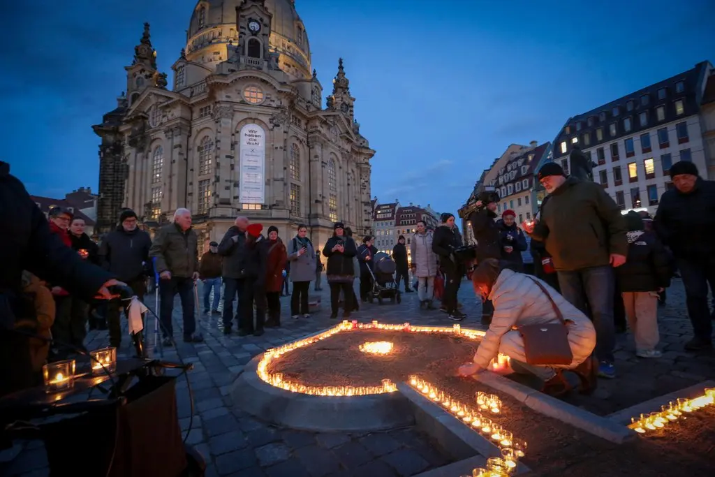 Menschen zünden Kerzen an vor der Frauenkirche in Dresden