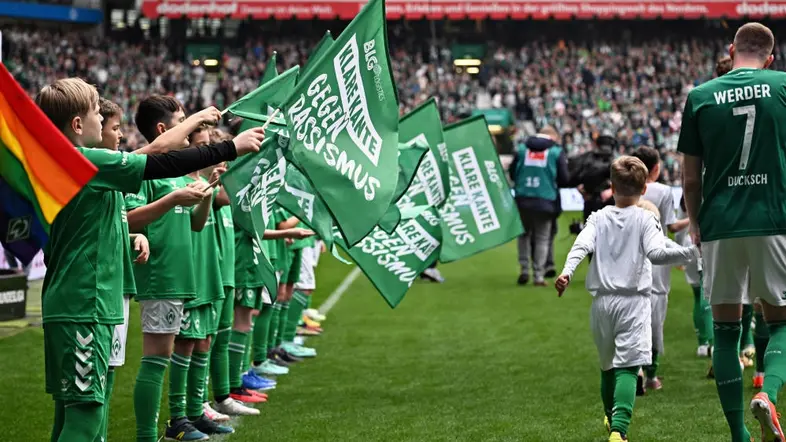 Flaggenkinder mit einem Statement gegen Rassismus begleiten den Einlauf