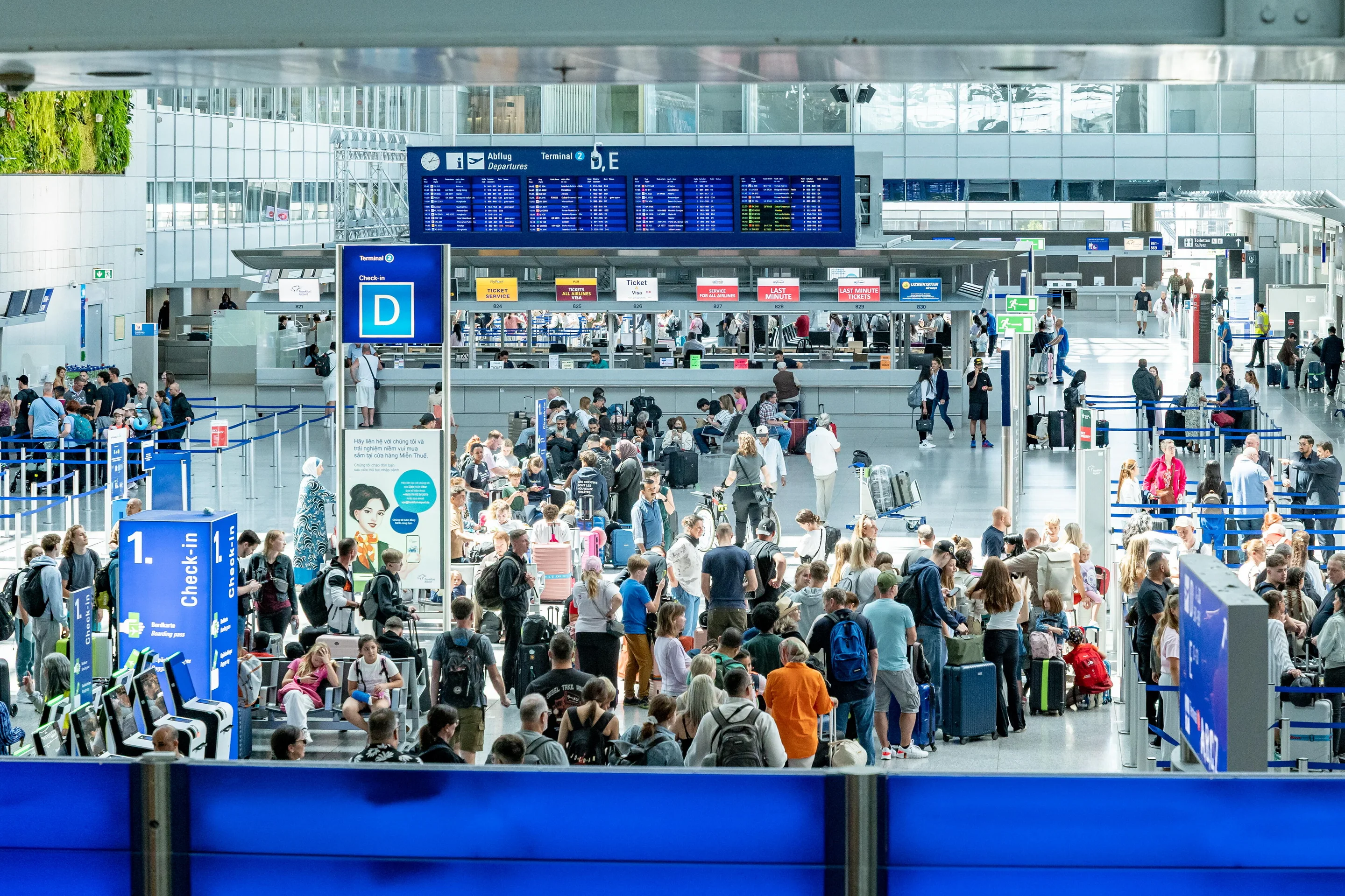Hunderte Menschen warten im Check-In-Bereich eines Flughafens