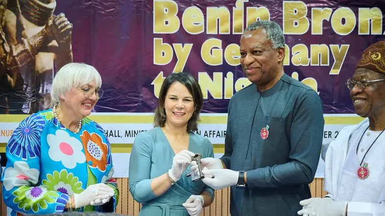 Claudia Roth, Annalena Baerbock, Geoffrey Onyeama und Alhaji Lai Mohammed stehen bei der Übergabe der Benin-Bronzen im Dezember 2022 im Außenministerium in Berlin zusammen.