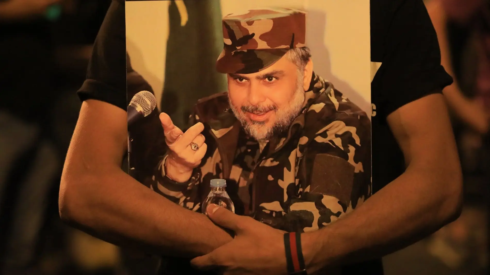 Plakat von Moktada al-Sadr in den Armen eines Anhängers Ein Anhänger hält ein Plakat von Moktada al-Sadr in den Armen.