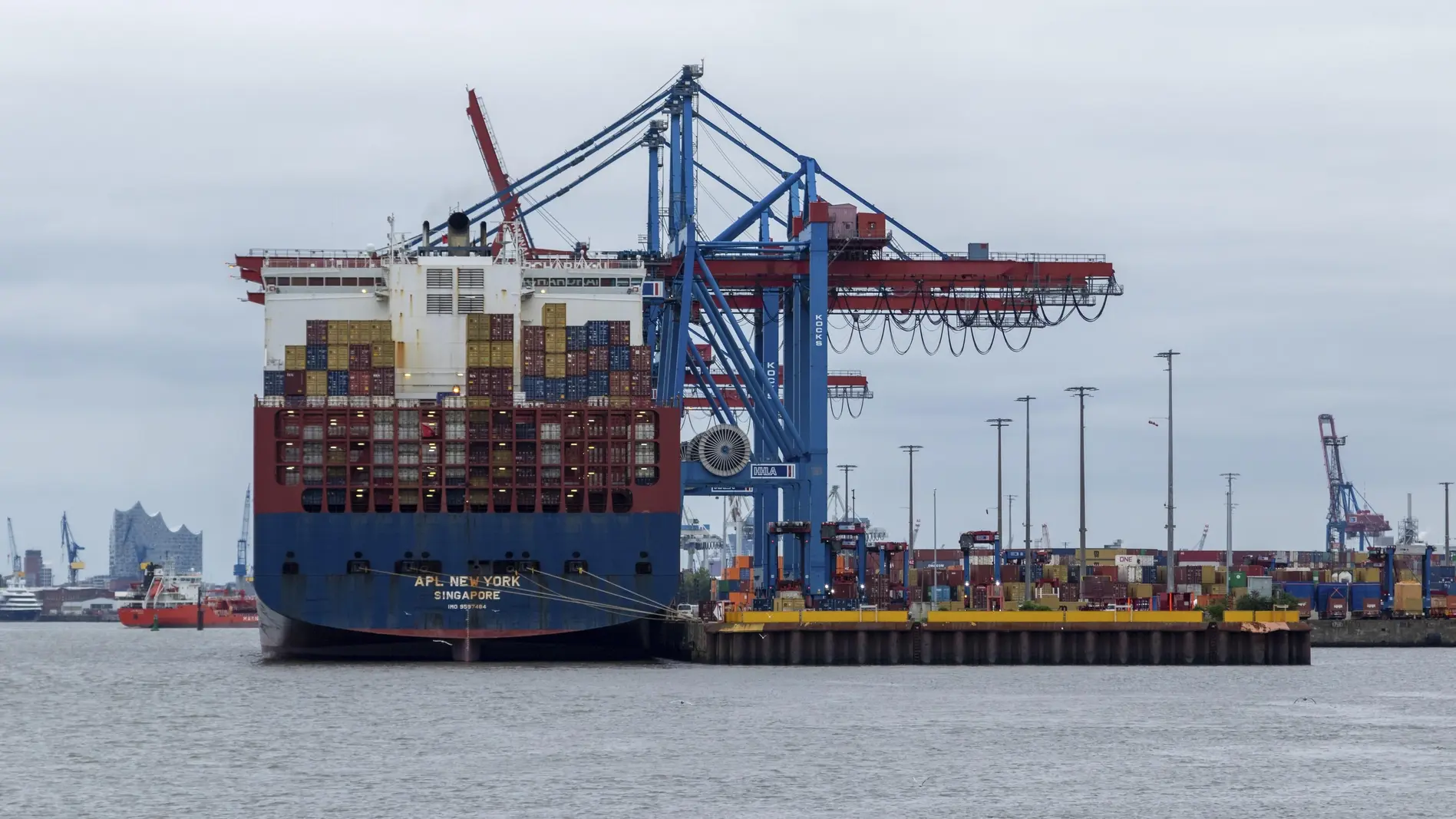 Containerschiff bei grauem Himmel im Hafen von Hamburg.
