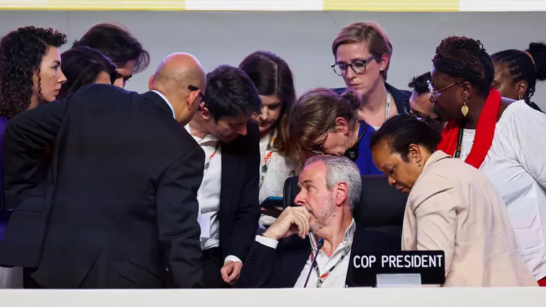 Der Präsident der Weltklimakonferenz steckt die Köpfe mit anderen Teilnehmern zusammen