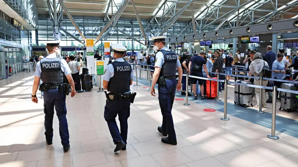Drei Bundespolizisten auf Streife im menschgefüllten Hamburger Flughafen