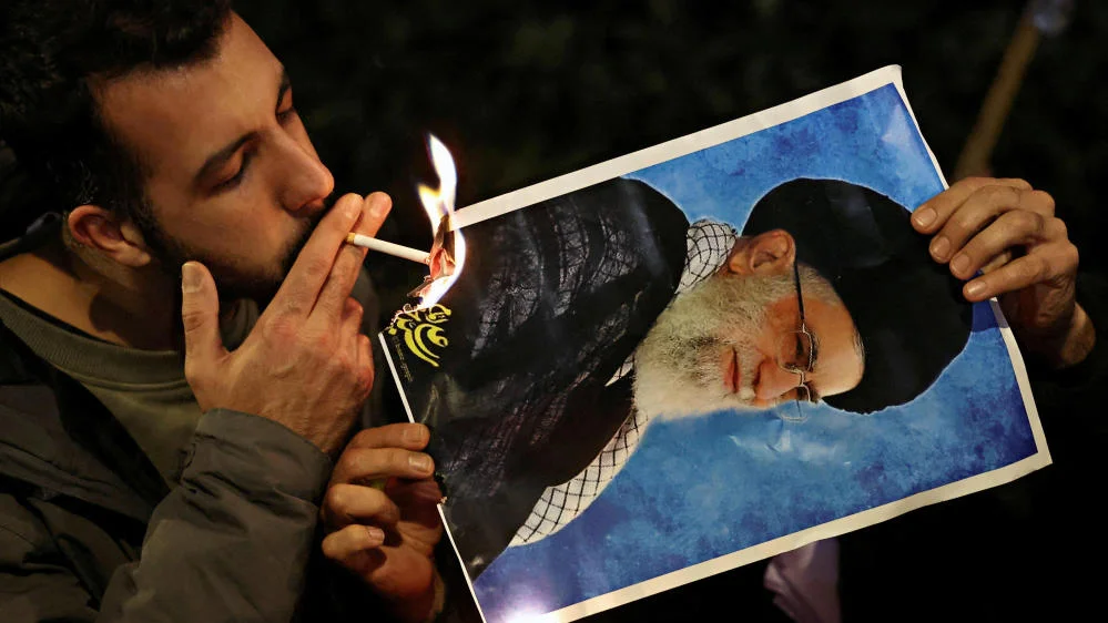 Mann zündet Plakat von Ayatollah Ali Khamenei mit einer Zigarette an