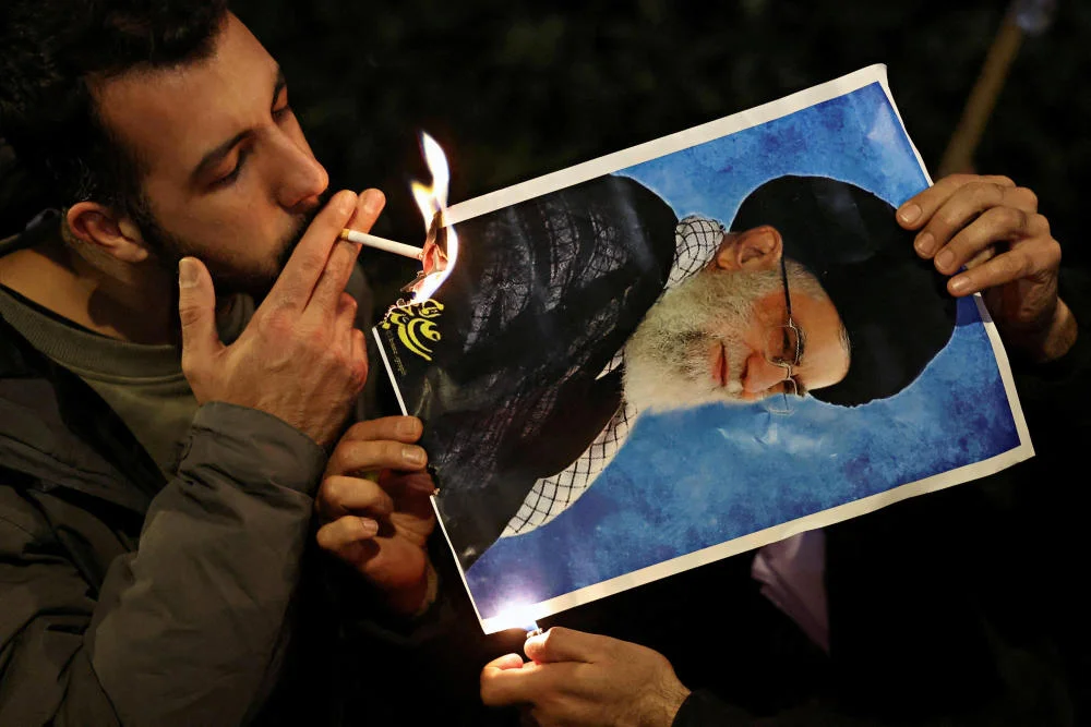 Mann zündet Plakat von Ayatollah Ali Khamenei mit einer Zigarette an