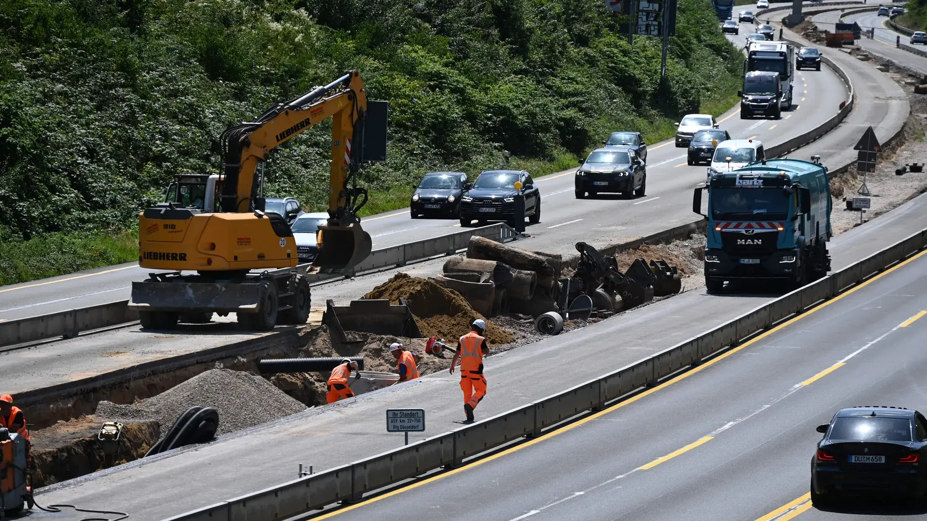 Bauarbeiter und Baumaschinen bei der Arbeit auf der Autobahnbaustelle der A59 