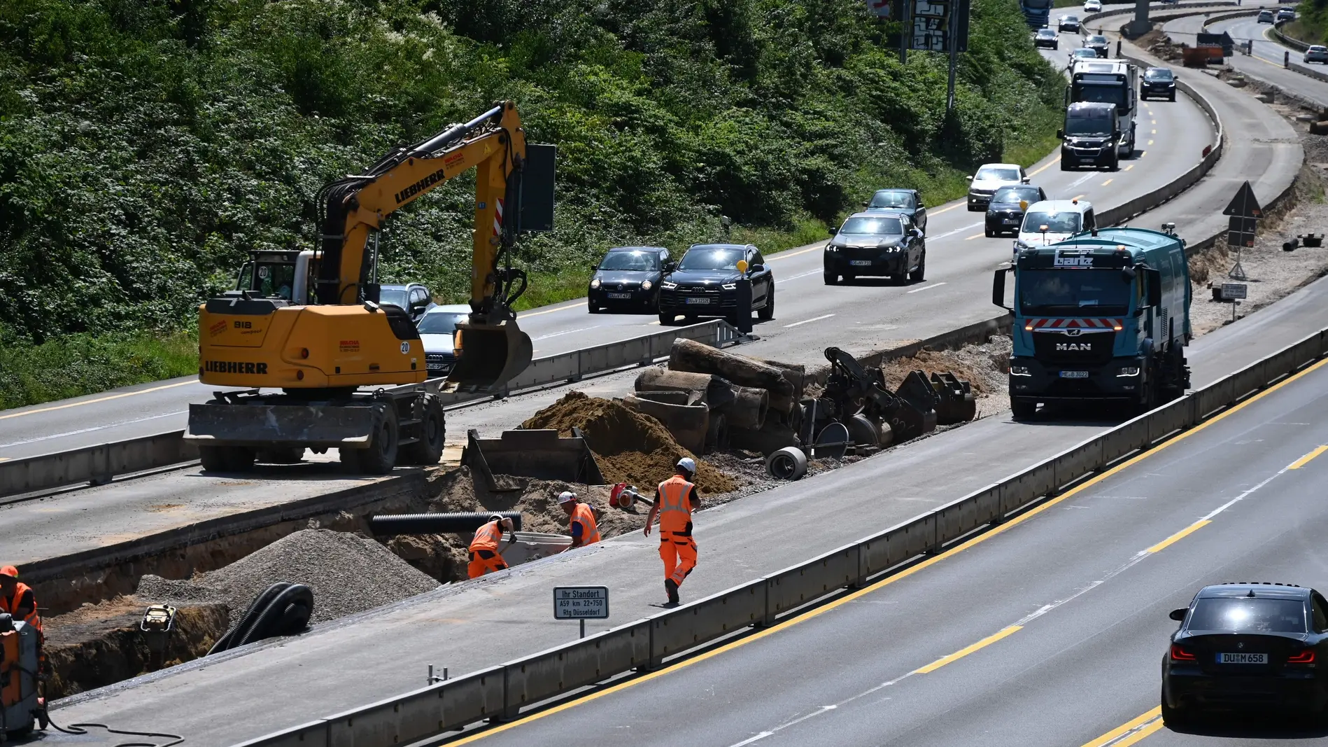 Bauarbeiter und Baumaschinen bei der Arbeit auf der Autobahnbaustelle der A59 