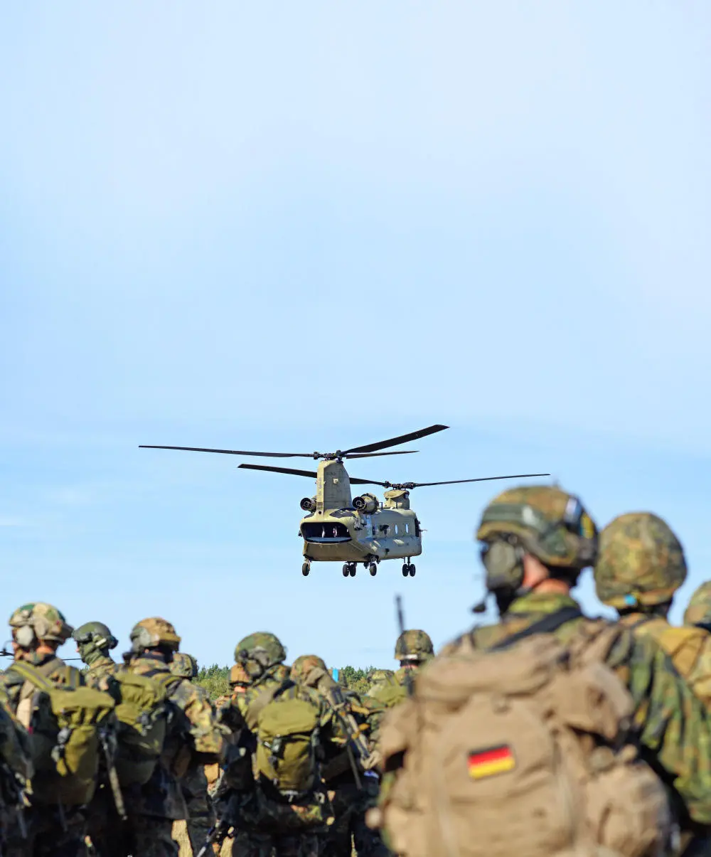 Ein Hubschrauber fliegt über Bundeswehrsoldaten hinweg.