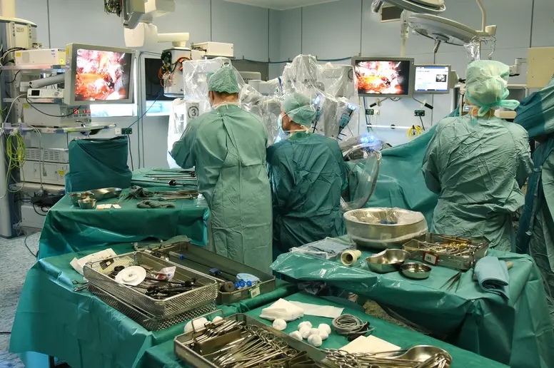 Blick in einen OP-Saal, viele Tische mit OP-Besteck und Menschen in grünen Roben