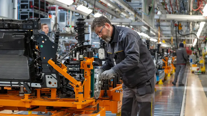 Ein Mann in Arbeitskleidung schraubt an einer Maschine