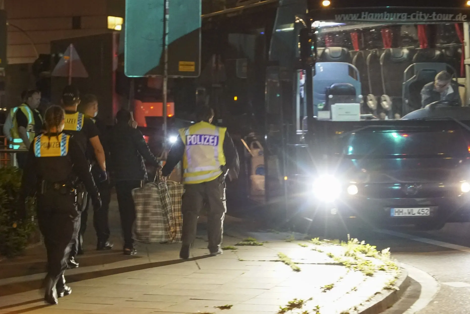 Polizisten in Uniform laufen in der Nacht auf einen Bus am Straßenrand zu.