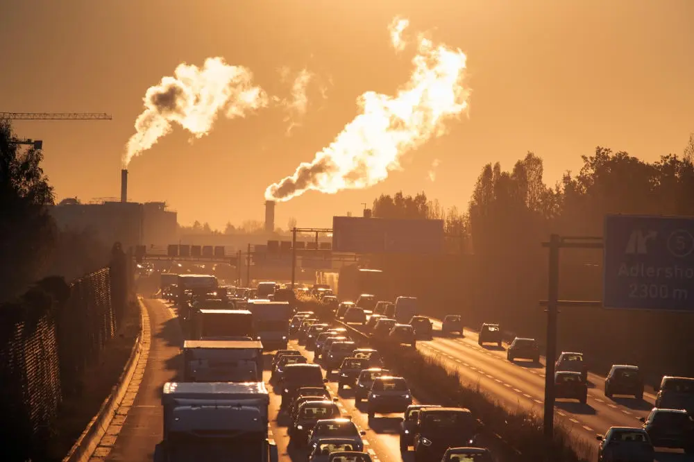 Stau im Morgenlicht auf einer Autobahn vor qualmenden Schornsteinen